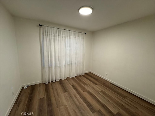 spare room with baseboards and wood finished floors