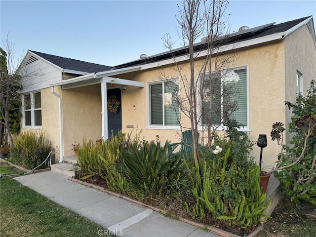 view of front of home featuring roof mounted solar panels and stucco siding