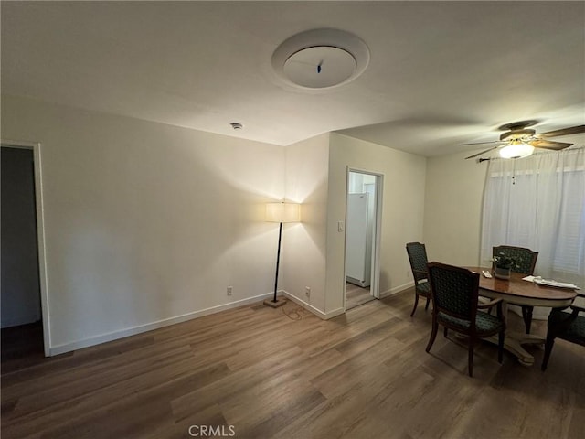 dining space featuring a ceiling fan, dark wood-style flooring, and baseboards