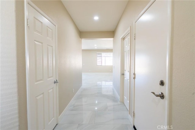 hallway with marble finish floor, recessed lighting, and baseboards