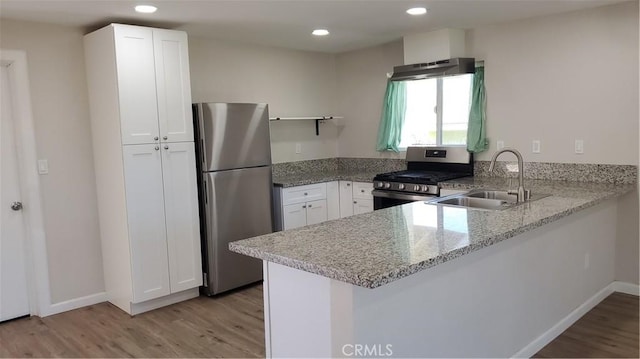 kitchen featuring a peninsula, appliances with stainless steel finishes, a sink, and white cabinetry