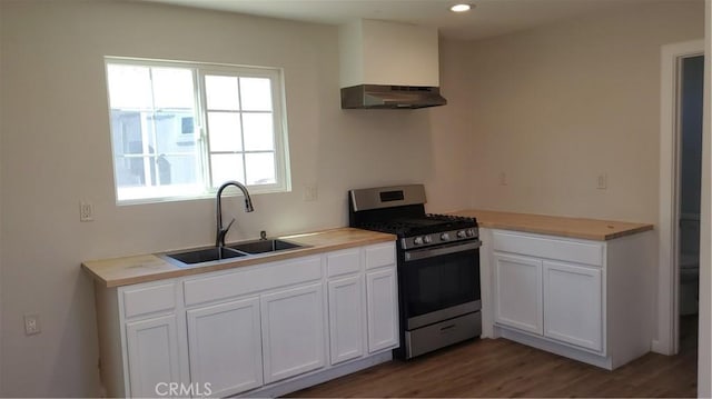 kitchen with a sink, wood counters, white cabinetry, and stainless steel range with gas stovetop