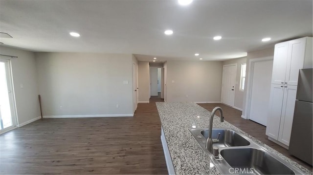 kitchen featuring recessed lighting, white cabinets, freestanding refrigerator, light stone countertops, and dark wood-style floors