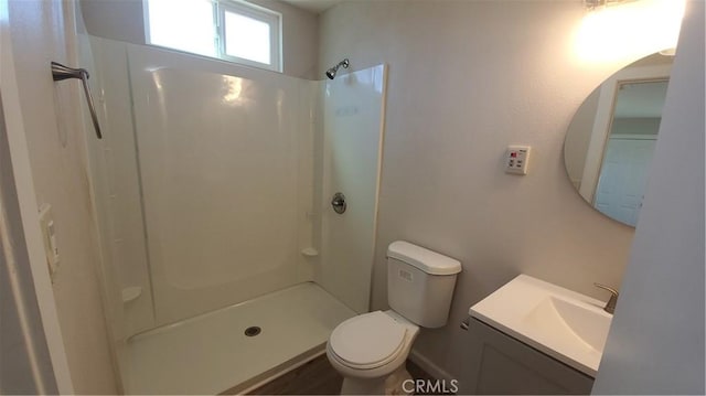 bathroom featuring toilet, walk in shower, and vanity