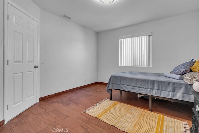 bedroom with visible vents, baseboards, and wood finished floors