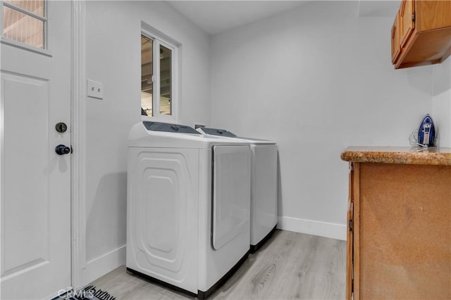 washroom with baseboards, separate washer and dryer, cabinet space, and light wood-style floors