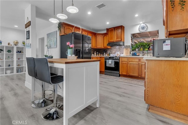 kitchen featuring visible vents, black fridge with ice dispenser, decorative backsplash, range with electric cooktop, and under cabinet range hood