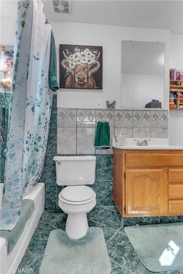 bathroom with shower / bath combo, visible vents, toilet, vanity, and tile walls