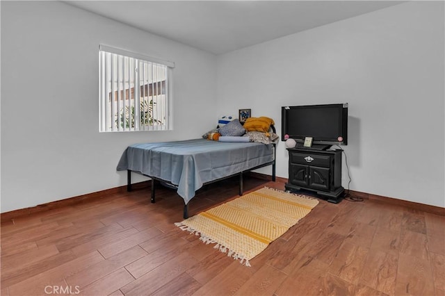 bedroom with wood finished floors and baseboards