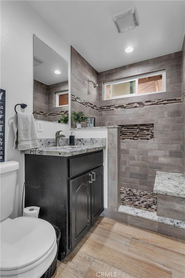 full bathroom featuring toilet, visible vents, a walk in shower, and vanity