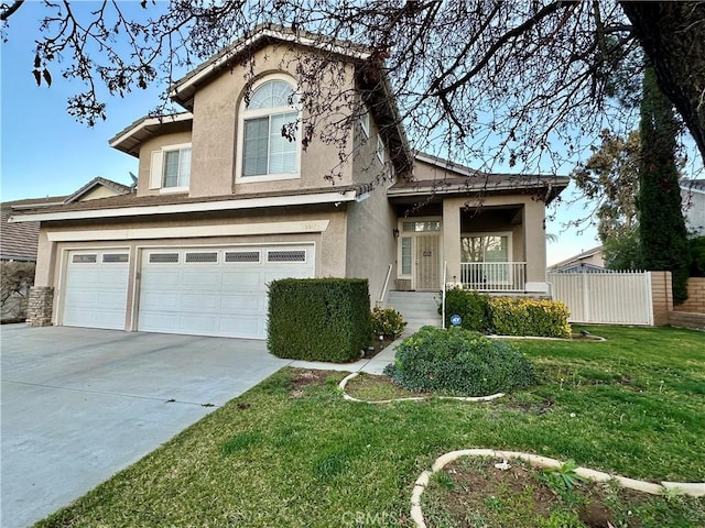 view of front facade with an attached garage, fence, driveway, stucco siding, and a front lawn