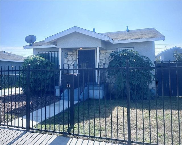 view of front of property featuring a fenced front yard, stone siding, and stucco siding