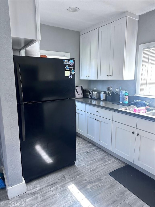 kitchen featuring freestanding refrigerator, white cabinetry, and light wood finished floors