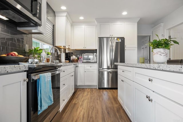 kitchen featuring stainless steel appliances, dark wood finished floors, light stone countertops, and white cabinets