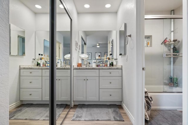 bathroom featuring enclosed tub / shower combo, ceiling fan, vanity, and baseboards