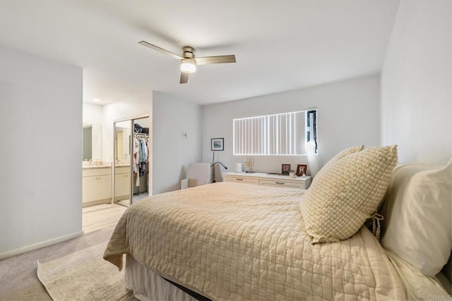 bedroom with a closet, light colored carpet, ceiling fan, ensuite bath, and baseboards