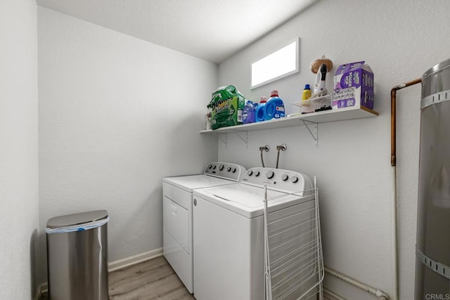 washroom featuring light wood-type flooring, laundry area, washing machine and dryer, and baseboards