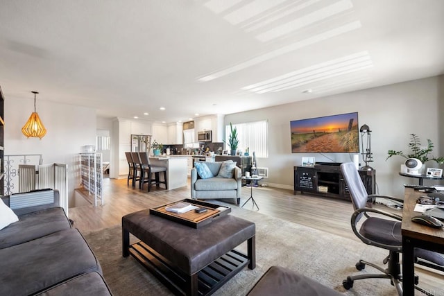 living area featuring recessed lighting, baseboards, and light wood finished floors