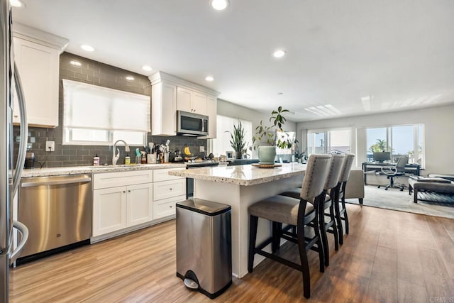 kitchen with open floor plan, stainless steel appliances, white cabinetry, and a center island