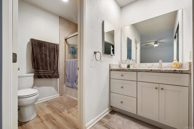 full bathroom featuring vanity, wood finished floors, a shower with shower door, and baseboards