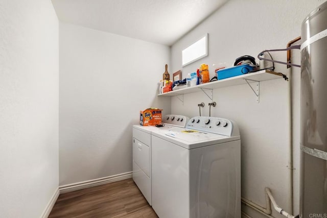 clothes washing area with washer and dryer, laundry area, baseboards, and wood finished floors