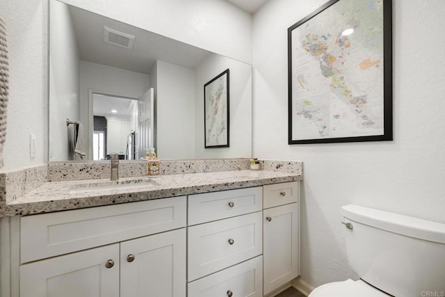 bathroom with toilet, visible vents, and vanity