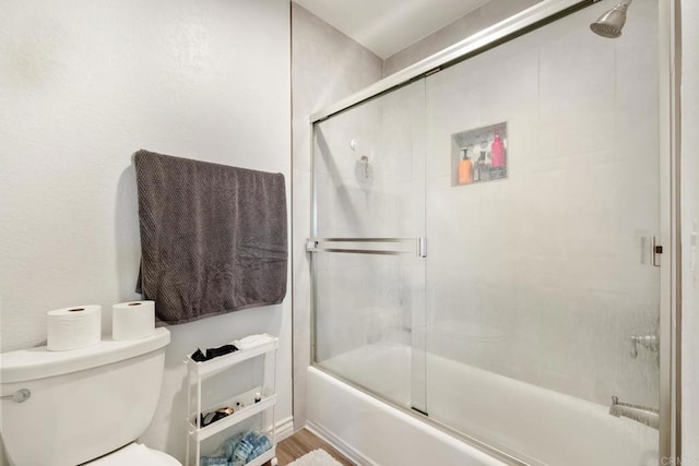 bathroom featuring toilet, enclosed tub / shower combo, and wood finished floors