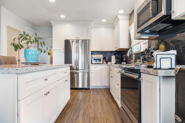 kitchen featuring dark wood finished floors, appliances with stainless steel finishes, light countertops, white cabinetry, and backsplash