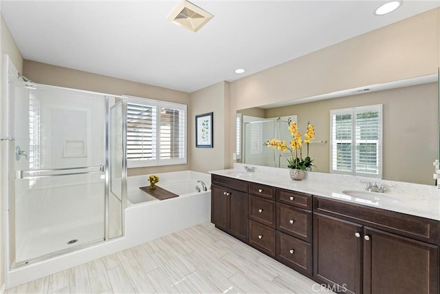 bathroom with double vanity, a stall shower, visible vents, a garden tub, and a sink