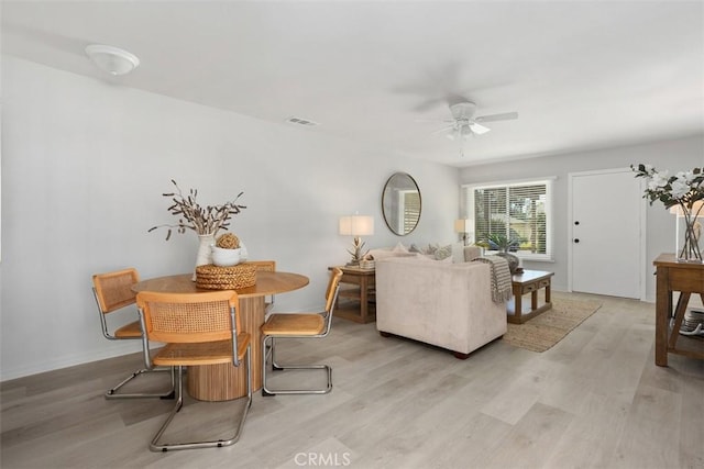 living room with baseboards, light wood-type flooring, visible vents, and a ceiling fan