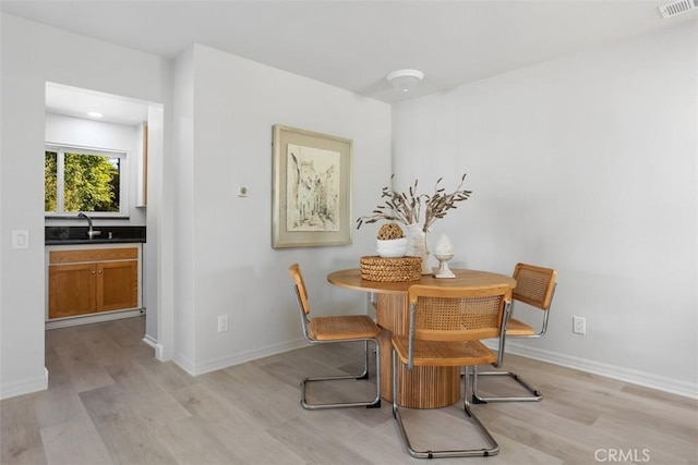 dining room featuring light wood finished floors, baseboards, and visible vents