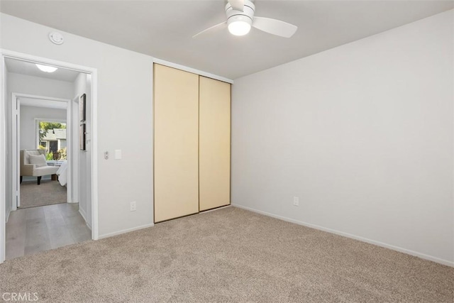 unfurnished bedroom featuring a closet, light carpet, ceiling fan, and baseboards