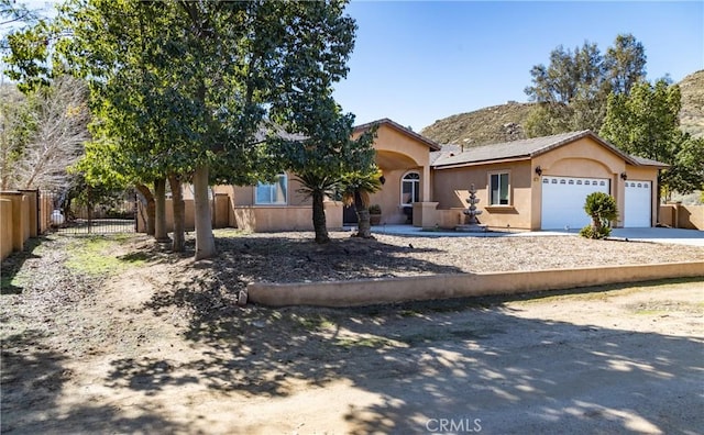 view of front facade with a garage, driveway, fence, and stucco siding