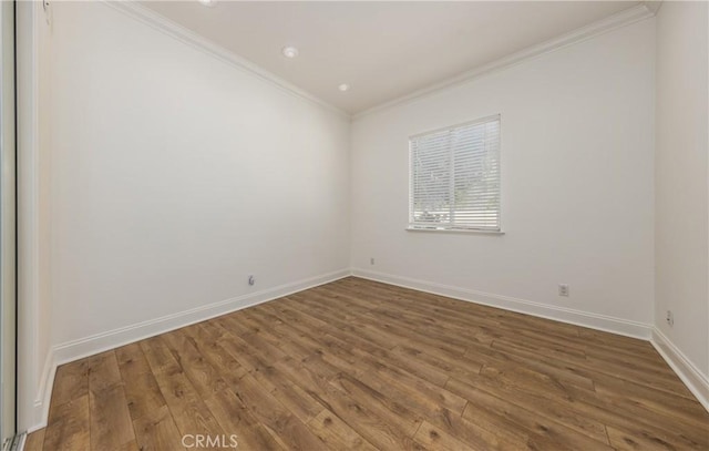 spare room with baseboards, wood finished floors, and crown molding