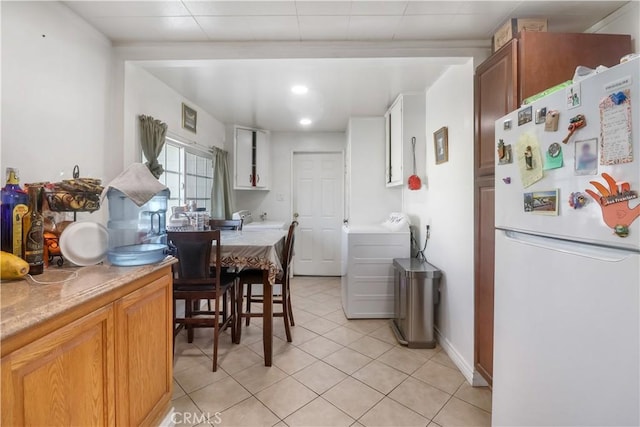 8181 Date St, Fontana, CA 92335 - kitchen featuring light tile patterned floors, light countertops, freestanding refrigerator, brown cabinetry, and washer / dryer