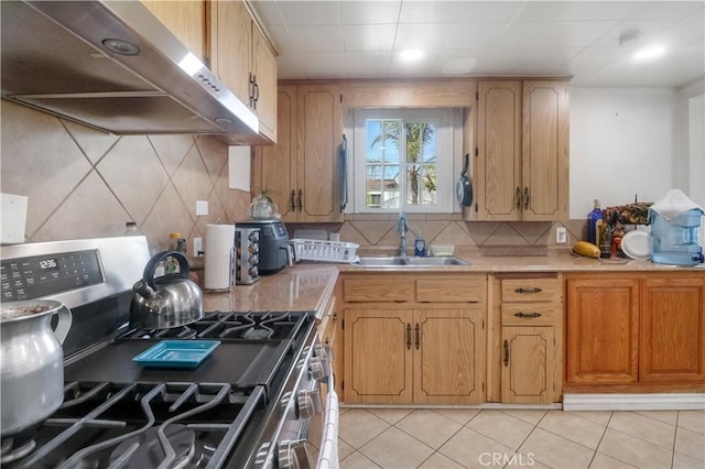 8181 Date St, Fontana, CA 92335 - kitchen with light tile patterned floors, stainless steel gas range oven, under cabinet range hood, a sink, and light countertops