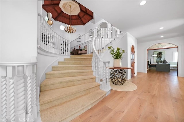 stairs with a chandelier, wood finished floors, and recessed lighting