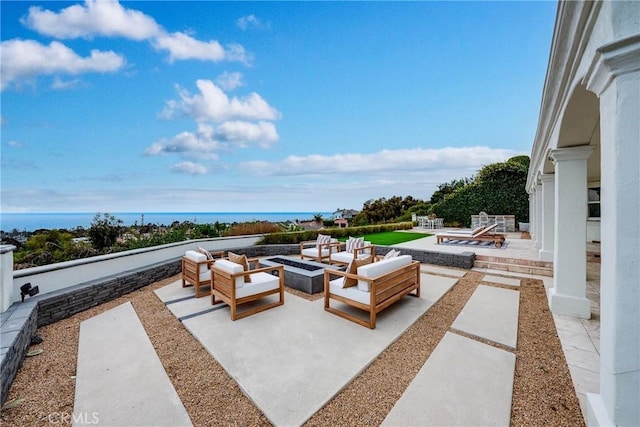 view of patio / terrace featuring a water view and an outdoor living space with a fire pit