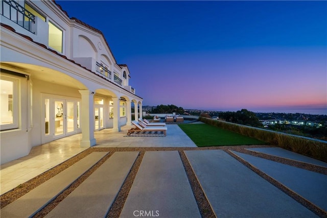 patio terrace at dusk featuring a balcony