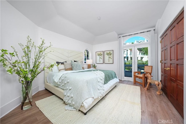 bedroom with access to exterior, light wood-type flooring, and baseboards