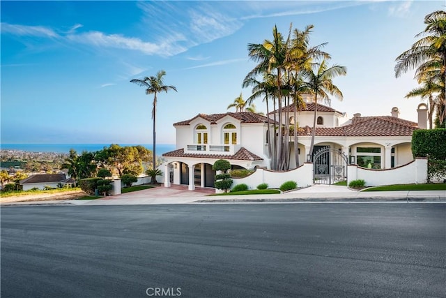 mediterranean / spanish home with fence, concrete driveway, a tiled roof, a gate, and stucco siding