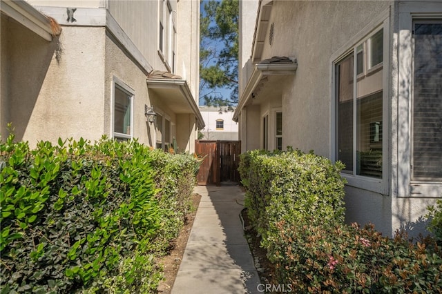 view of side of property featuring fence and stucco siding