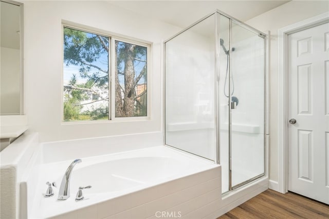 full bath with a stall shower, a bath, and wood finished floors