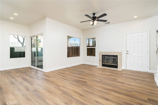 unfurnished living room featuring a tile fireplace, visible vents, light wood-style flooring, and baseboards