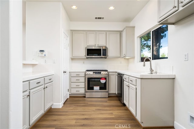 kitchen featuring recessed lighting, wood finished floors, visible vents, appliances with stainless steel finishes, and tile counters