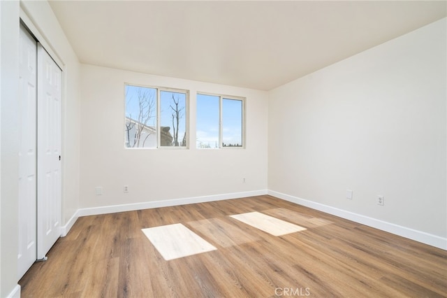 unfurnished bedroom with a closet, baseboards, and wood finished floors