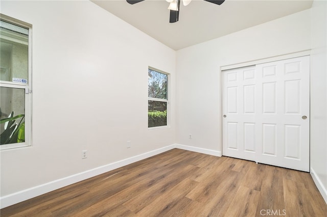 unfurnished bedroom with a ceiling fan, a closet, baseboards, and wood finished floors