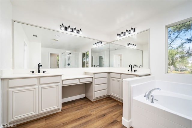 bathroom with a garden tub, vanity, and wood finished floors