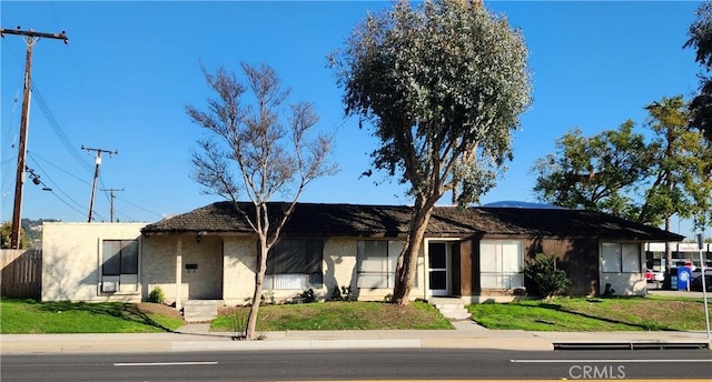 ranch-style home featuring fence, a front lawn, and stucco siding