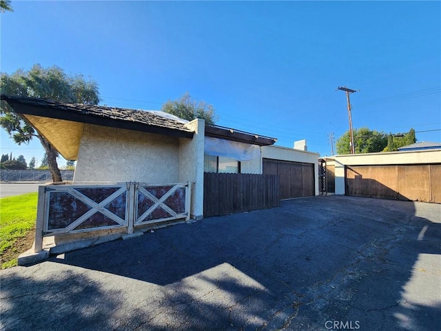 view of side of home featuring a gate, fence, and stucco siding